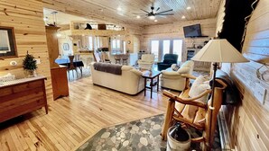 A cozy log cabin interior with a living room, dining area, and kitchen.