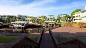 Een resort met meerdere gebouwen, een houten looppad en palmbomen.