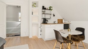 A modern kitchen with white cabinetry, a round dining table, and black chairs. - Møllehuset (Ikast)