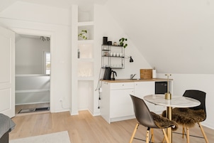Una cocina moderna con armarios blancos, una mesa de comedor redonda y sillas negras.