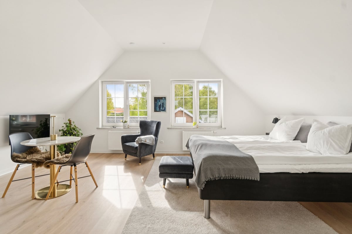 Un dormitorio con una cama, una silla, una mesa y un televisor.