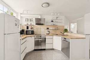Una cocina moderna con armarios blancos, electrodomésticos de acero inoxidable y encimera de madera.
