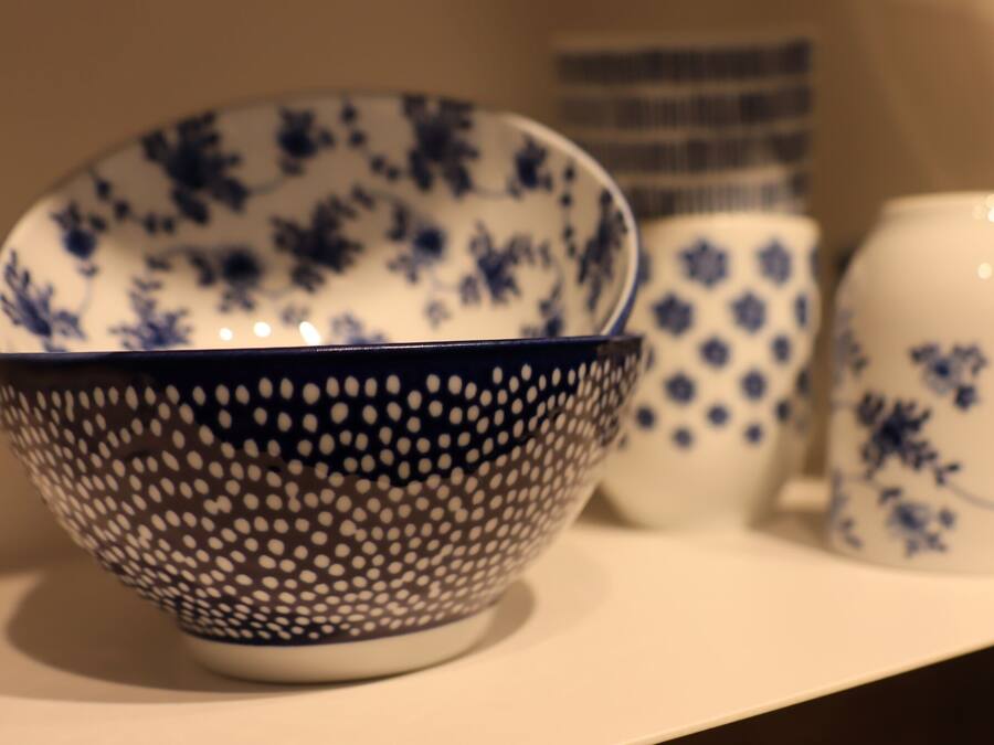 A collection of ceramic bowls and a vase on a shelf.