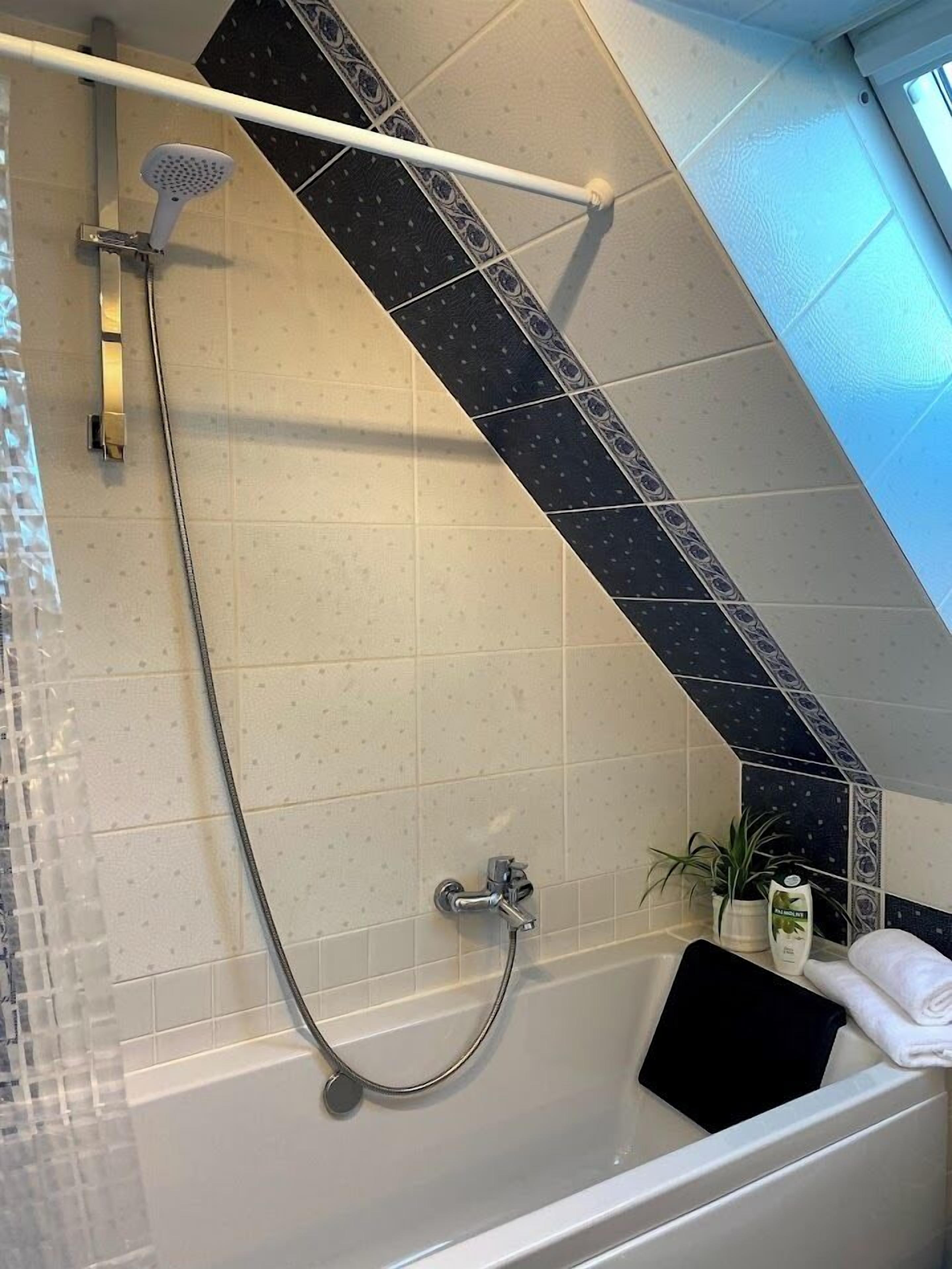 Un espacio de ducha con cabezal de ducha de mano, cabezal de ducha empotrado y una bañera.