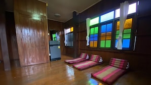 A room with wooden floors, a sofa, a small table, and a TV. - Ho Hostel (Chiang Mai)