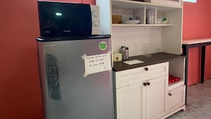 A kitchen with a refrigerator, microwave, and white cabinets. - Ho Hostel (Chiang Mai)