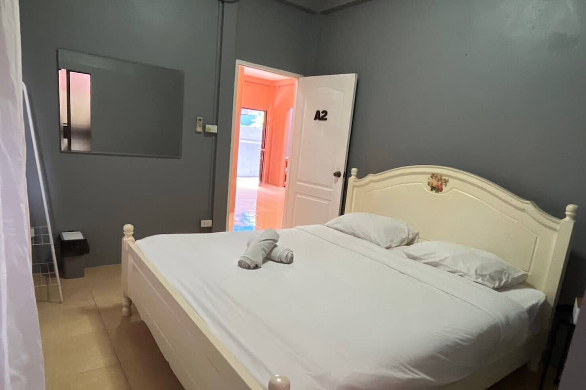 Un dormitori amb un llit gran, una porta amb la inscripció "A2" i un mirall a la paret.