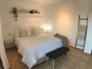 A bedroom with a bed, bedside tables, a bench, a ladder, and a shelf with decorative items. - Villa with pool La Cálida (Águilas)
