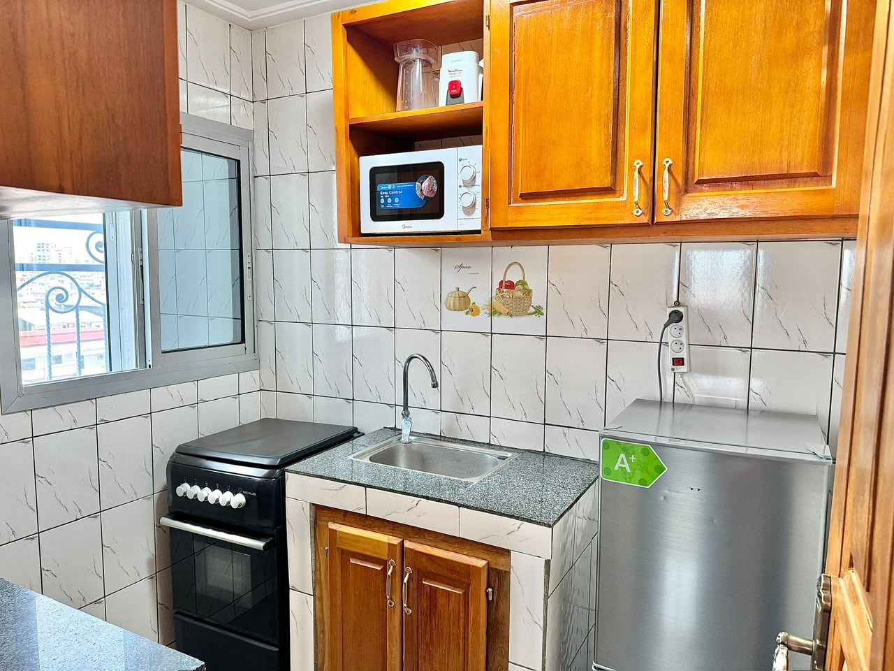 Cocina compacta con estufa, fregadero, microondas y refrigerador.