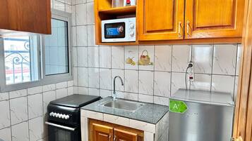 Cocina compacta con estufa, fregadero, microondas y refrigerador.