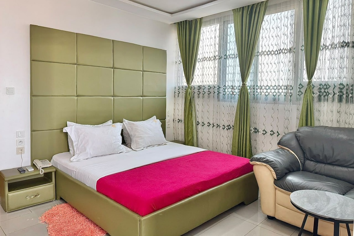Een slaapkamer met een bed, nachtkastje en een stoel.