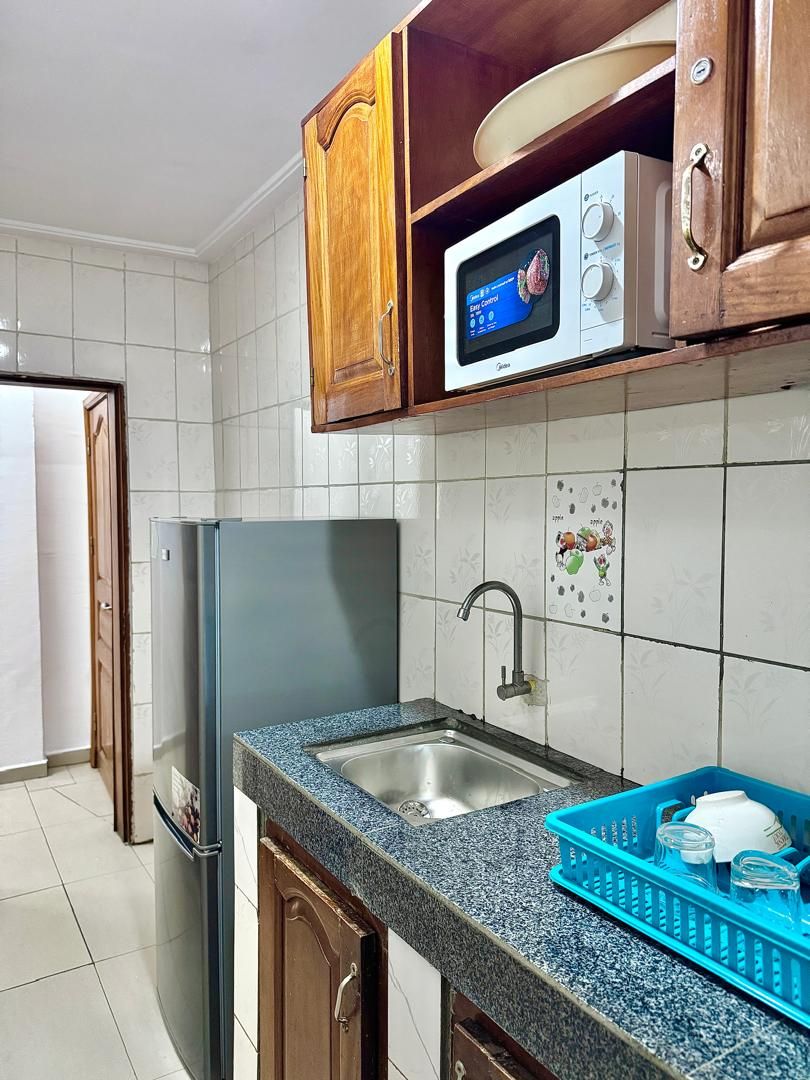 A kitchen with a refrigerator, a microwave, a sink, and cabinets.