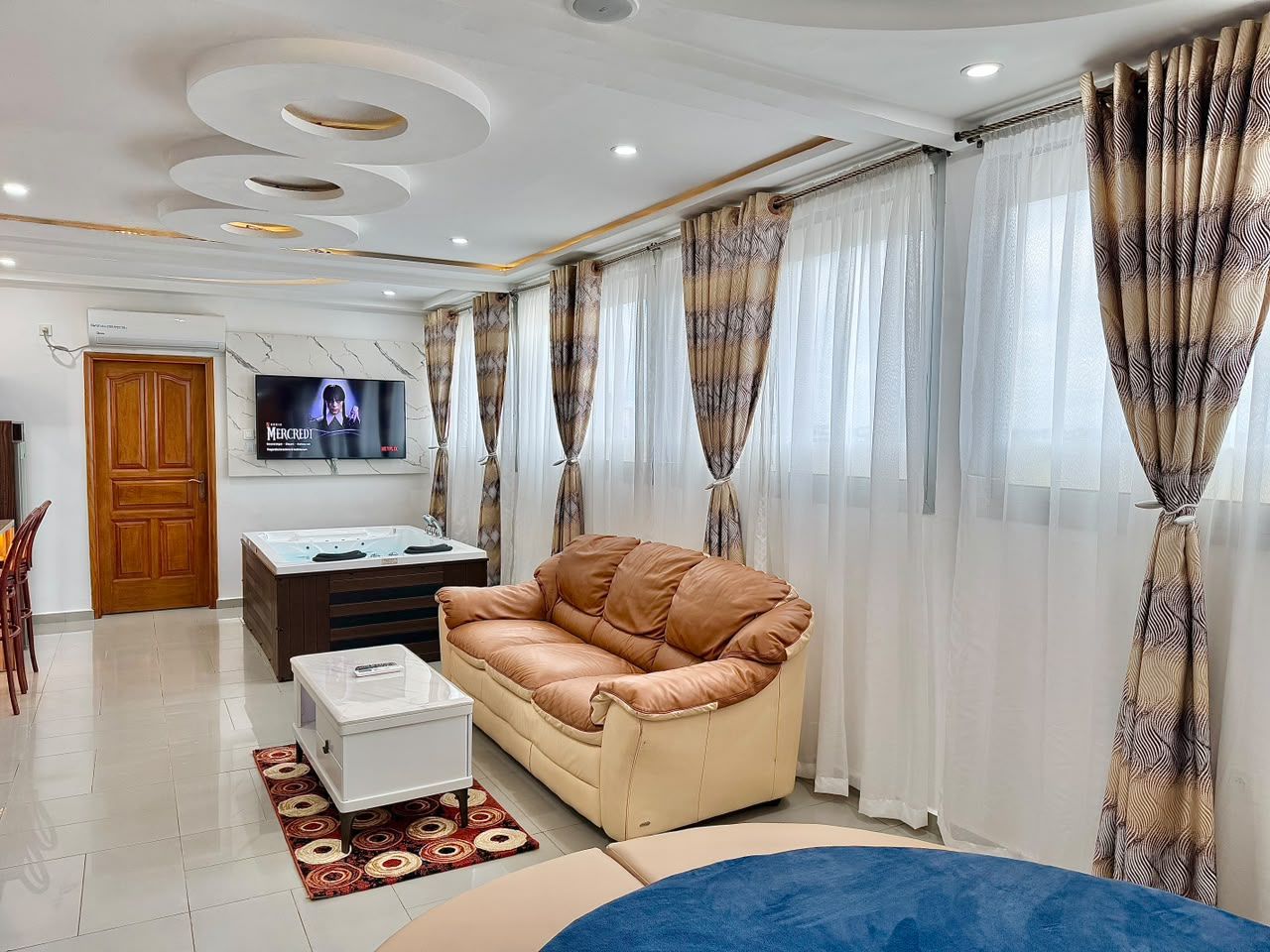 Una sala de estar con un sofá, una mesa de centro, un televisor y cortinas.