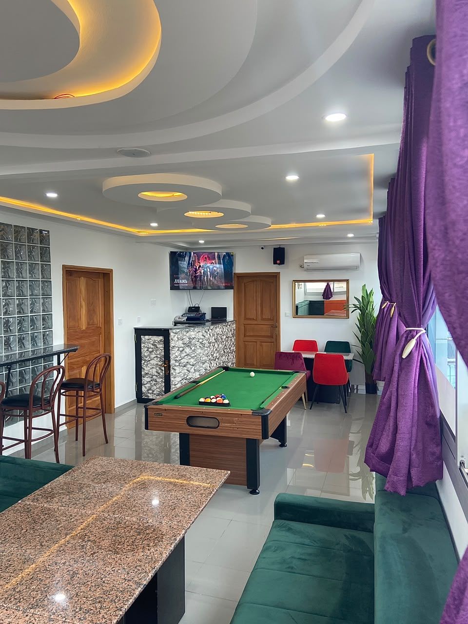 Una sala de billar con mesa de pool, sillas y televisión.