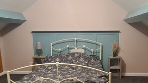 A bedroom with a bed, wooden cabinets, and a blue headboard. - Charming 1-bed Apartment in Barnsley (Barnsley)