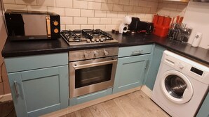 A kitchen with a gas stove, oven, microwave, and washing machine. - Charming 1-bed Apartment in Barnsley (Barnsley)