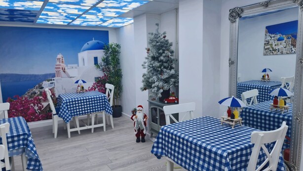 A room with a view of a blue sky and white buildings, checkered tablecloths, white chairs, and a small Christmas tree. - Charming 1-bed Apartment in Barnsley (Barnsley)