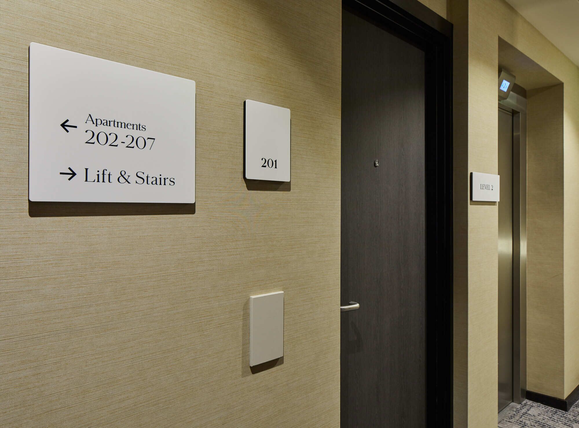 A hallway with directional signs for 'Apartments 202-207' and 'Lift & Stairs', and a door labeled '201'.