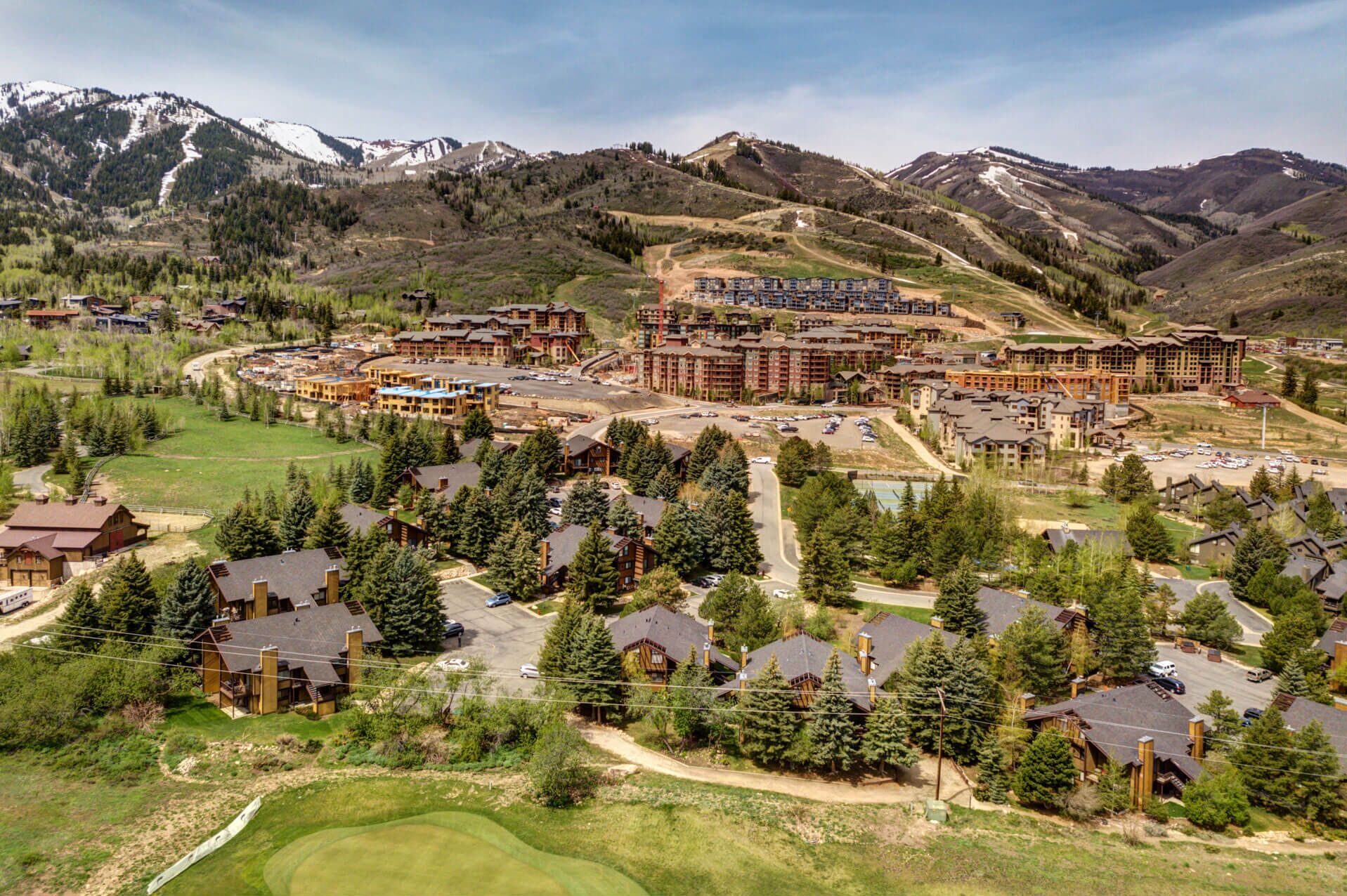 A resort with multiple buildings, including a large lodge and smaller cabins, surrounded by mountains and greenery.