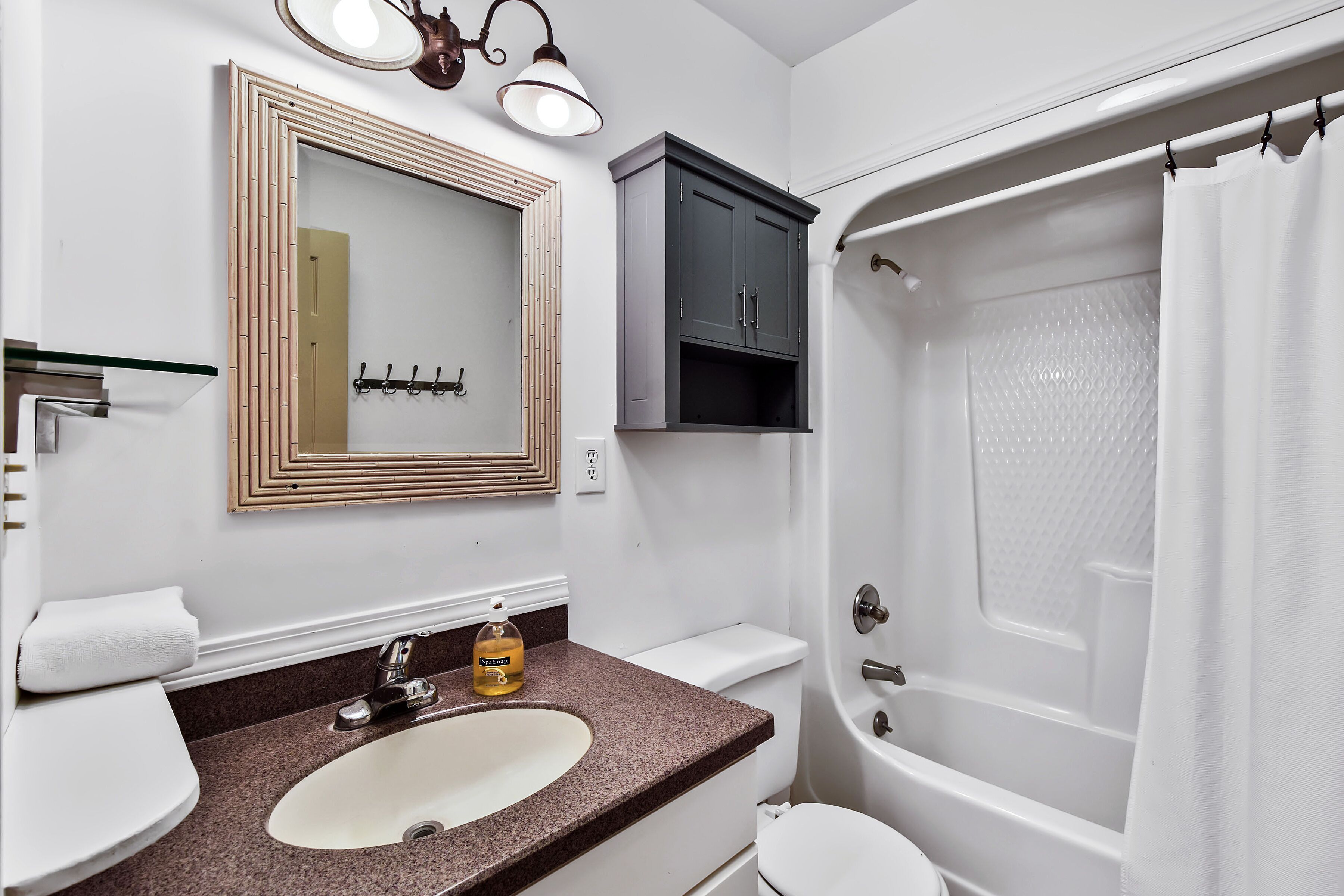 A bathroom with a sink, mirror, cabinet, toilet, and bathtub.