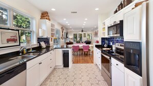 A modern kitchen with white cabinets, black countertops, and a hexagonal patterned floor. - 450 ft to East Beach • 2 Kings • Pet Friendly • Sleeps 6 • St. Simons Island (Saint Simons Island)