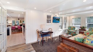 A spacious living area with a dining table, chairs, a sofa, and a television. - 450 ft to East Beach • 2 Kings • Pet Friendly • Sleeps 6 • St. Simons Island (Saint Simons Island)