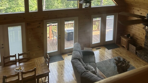 A spacious loft with a high ceiling, large windows offering a view of the outdoors, a dining area, and a cozy seating area. - Mountain Home with Views for Miles!!! (Murphy)