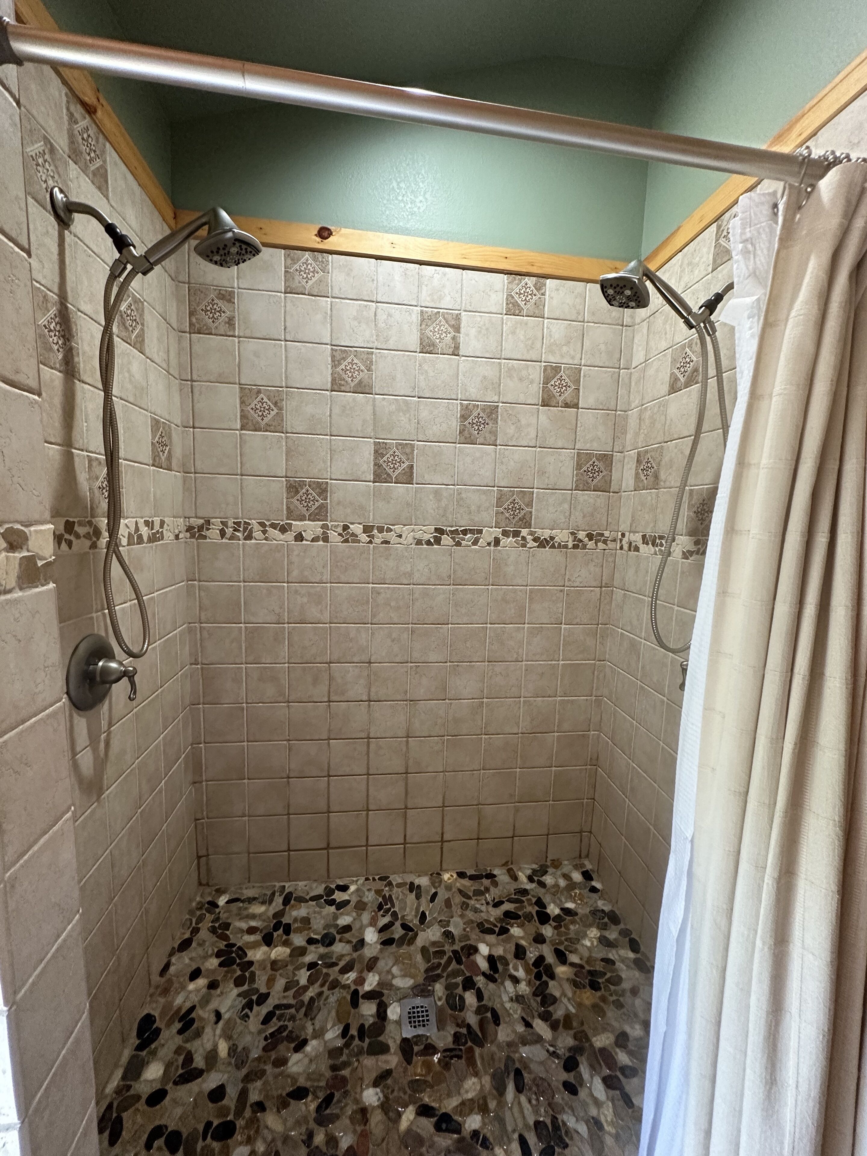 Eine Dusche mit gefliestem Boden und Duschkopf.