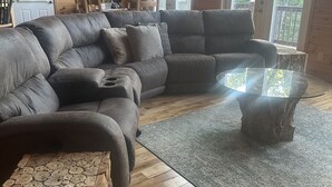 A cozy living room with a large sectional sofa, a glass coffee table, and a wooden side table. - Mountain Home with Views for Miles!!! (Murphy)