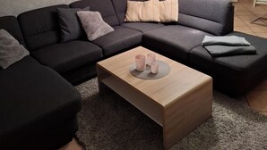 A modern living room with a sectional sofa, a wooden coffee table, and a floor lamp. - Gemütliche Ferienwohnung im Grünen, in der Nähe von Lüneburg (Melbeck)