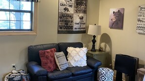 A cozy cabin interior with a dark blue sofa, patterned rug, and a poster on the wall.