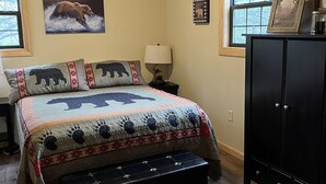 A bedroom with a bed, a nightstand, a dresser, and a window with curtains.
