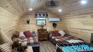A cozy cabin with two beds, a sofa, a foosball table, and a bear-themed decor.