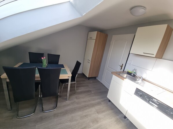A compact kitchen with a dining area, a built-in oven, and a white door with a brass handle.
