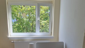 A bedroom with a single bed, a nightstand, a lamp, a radiator, and a window with a view of trees. - Monteurzimmer Gelnhausen, Ferienwohnung, Auch für Große Gruppen, Nähe Frankfurt (Gelnhausen)