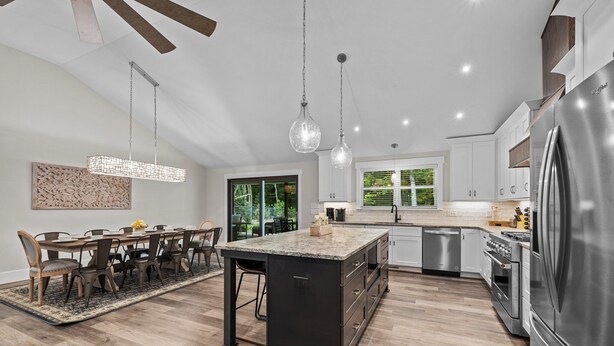 A modern kitchen with a central island, stainless steel appliances, and a dining area with a large table and chairs. - Stunning Home, conveniently located in Raleigh (Raleigh)