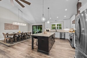A modern kitchen with a central island, stainless steel appliances, and a dining area with a large table and chairs. - Stunning Home, conveniently located in Raleigh (Raleigh)