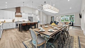 A spacious kitchen with modern appliances, a dining area with a wooden table set for six, and a large window offering a view of the outdoors. - Stunning Home, conveniently located in Raleigh (Raleigh)