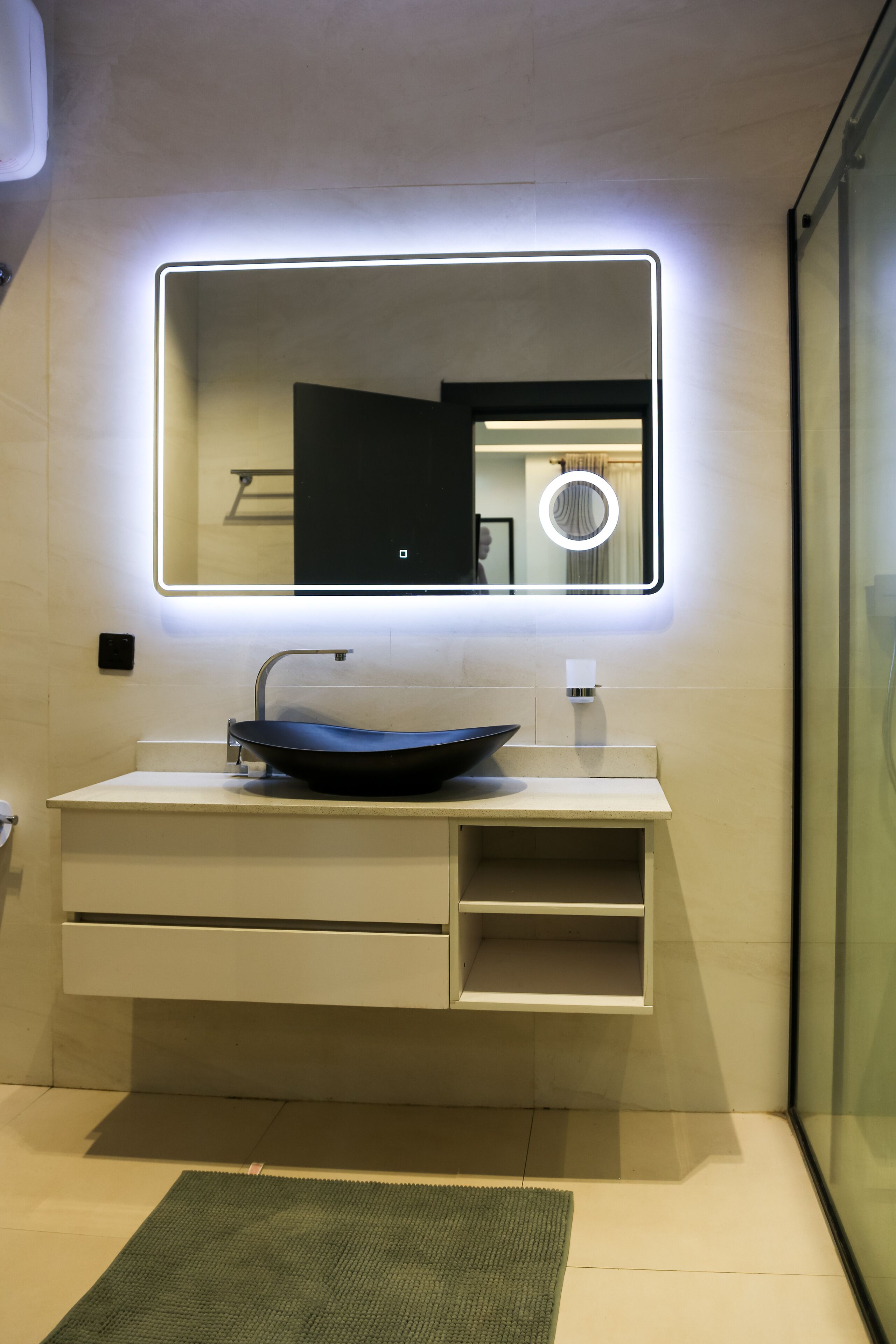 Un baño moderno con un lavamanos elegante, un espejo con iluminación integrada y una cabina de ducha de vidrio.