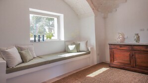 Ein Zimmer mit einer eingebauten Sitzbank unter einem Fenster, einem Holzschrank und einem Teppich mit Struktur.