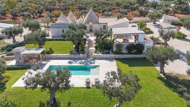 Eine großzügige Villa mit Swimmingpool, mehreren Gebäuden und einem gepflegten Garten.