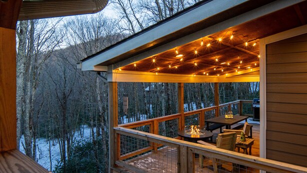 Eine Holzterrasse mit Tisch und Stühlen, mit Blick auf eine verschneite Landschaft.