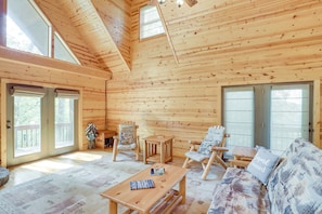 Ein Holzblockhaus im Inneren mit einer Couch, zwei Stühlen, einem Tisch und einer kleinen Holzbank.