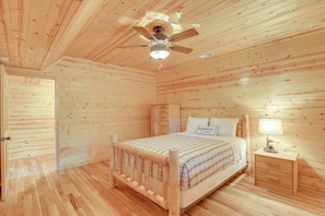 Ein Schlafzimmer mit Holzwandverkleidung, einem Bett, einem Nachttisch und einem Deckenventilator.