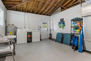 A laundry room with a washing machine, dryer, and stacked laundry baskets. - Private Heated Salt Water Pool Oasis • 10 Mins to Clearwater Beach (Clearwater)