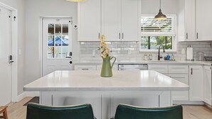 Una cocina moderna con armarios blancos, una isla central e iluminación colgante.