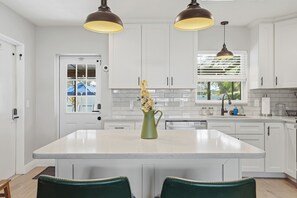 Una cocina moderna con armarios blancos, una isla central e iluminación colgante.
