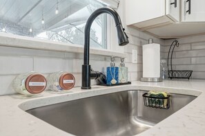A kitchen sink with a modern faucet, two soap dispensers, and a paper towel holder. - Private Heated Salt Water Pool Oasis • 10 Mins to Clearwater Beach (Clearwater)