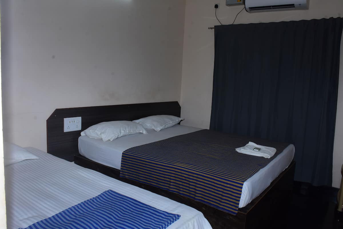 Ein Zimmer mit zwei Betten, einem dunklen Vorhang und einer Wandklimaanlage.