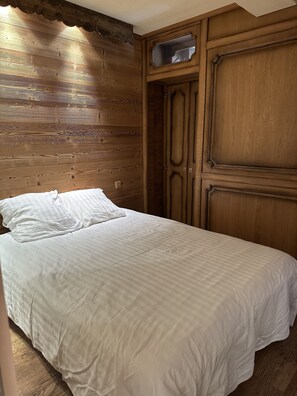 Cozy retreat with a large bed and traditional design, featuring a wooden wardrobe and mirror.